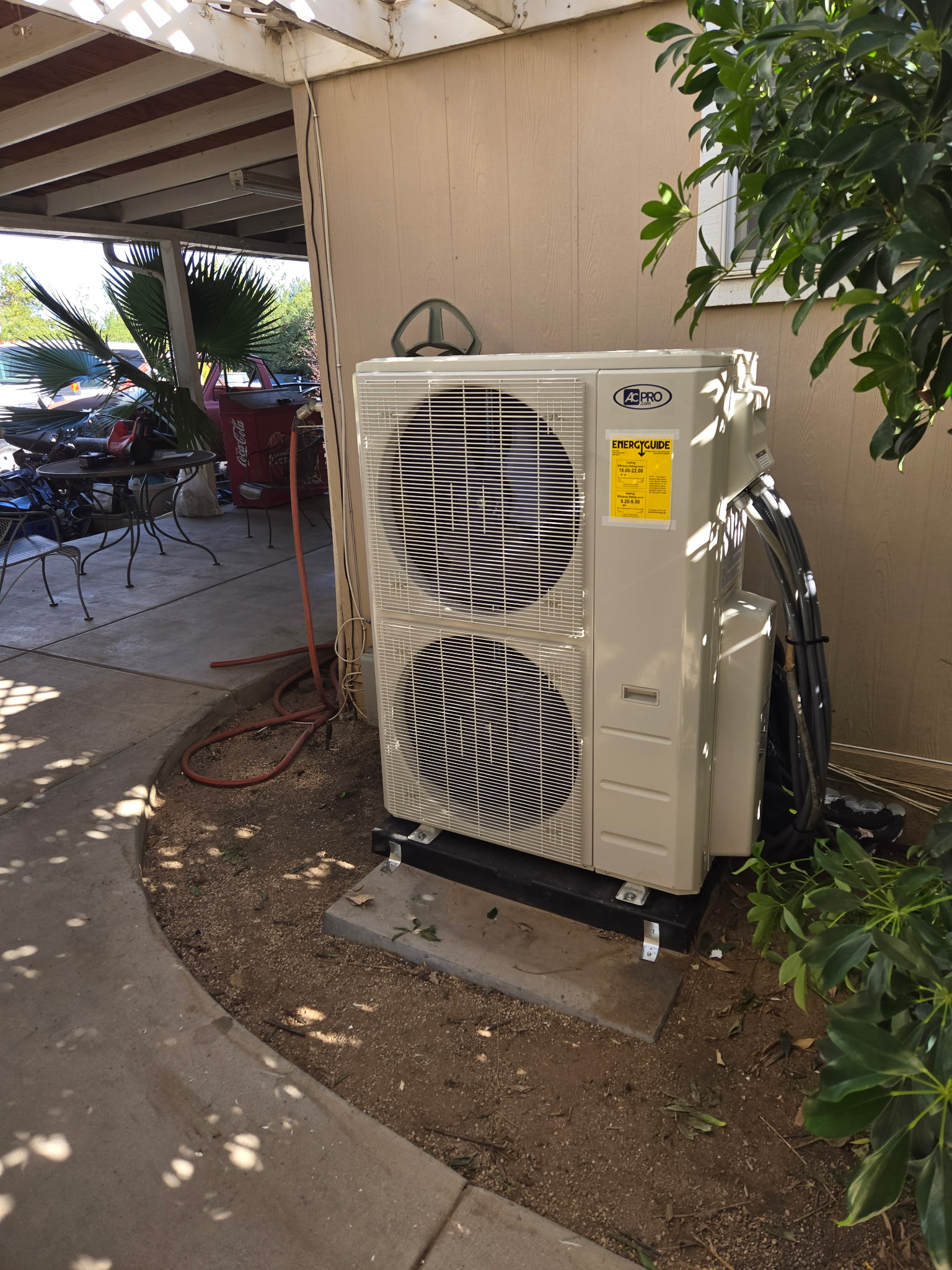 Residential outdoor air conditioning condenser installed on a concrete pad beside a home